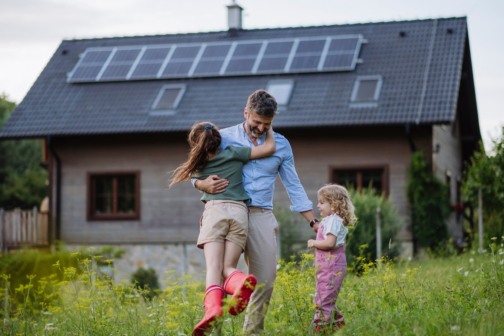  Vater mit Kindern vor saniertem Haus 