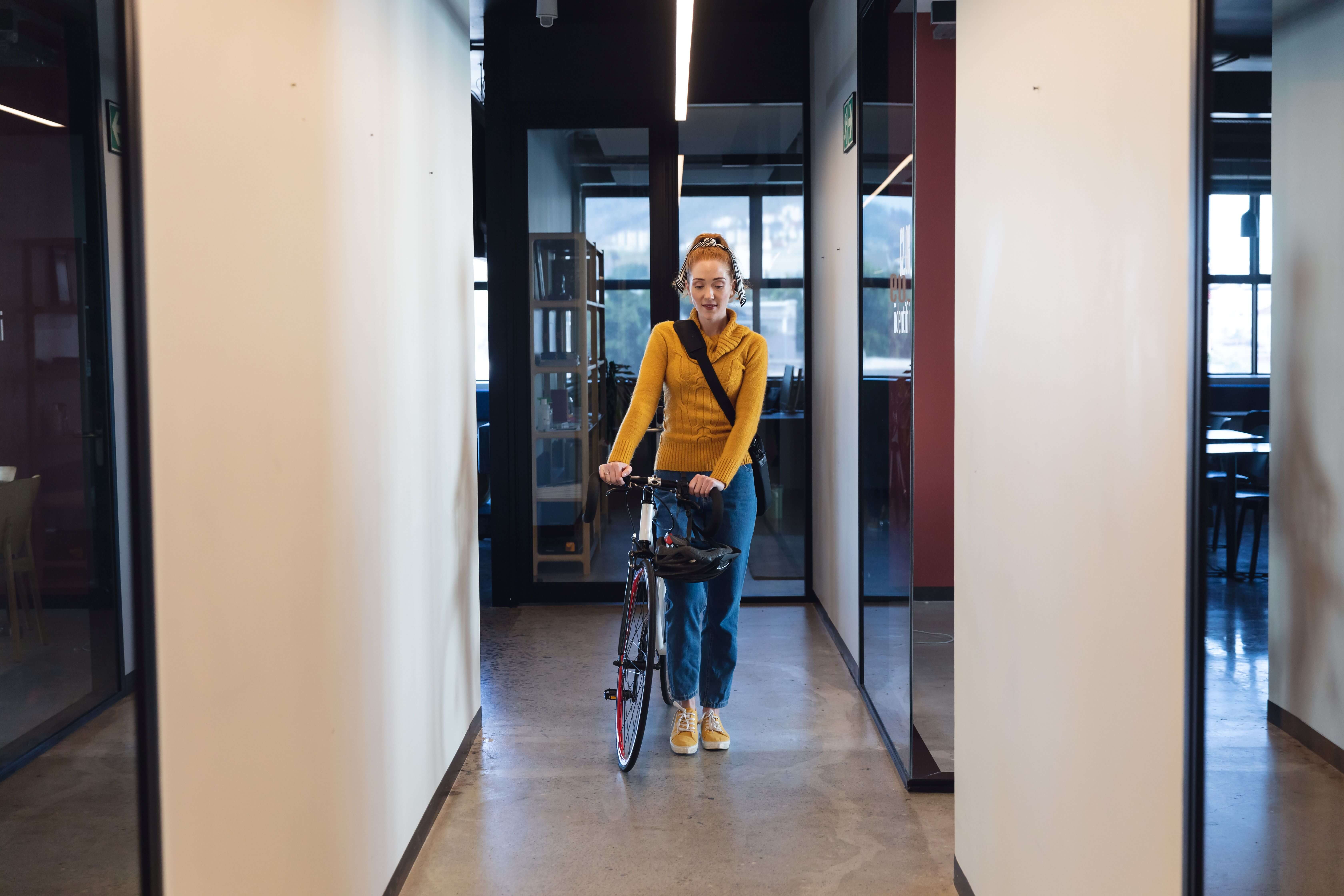  Frau kommt mit Fahrrad ins Büro 