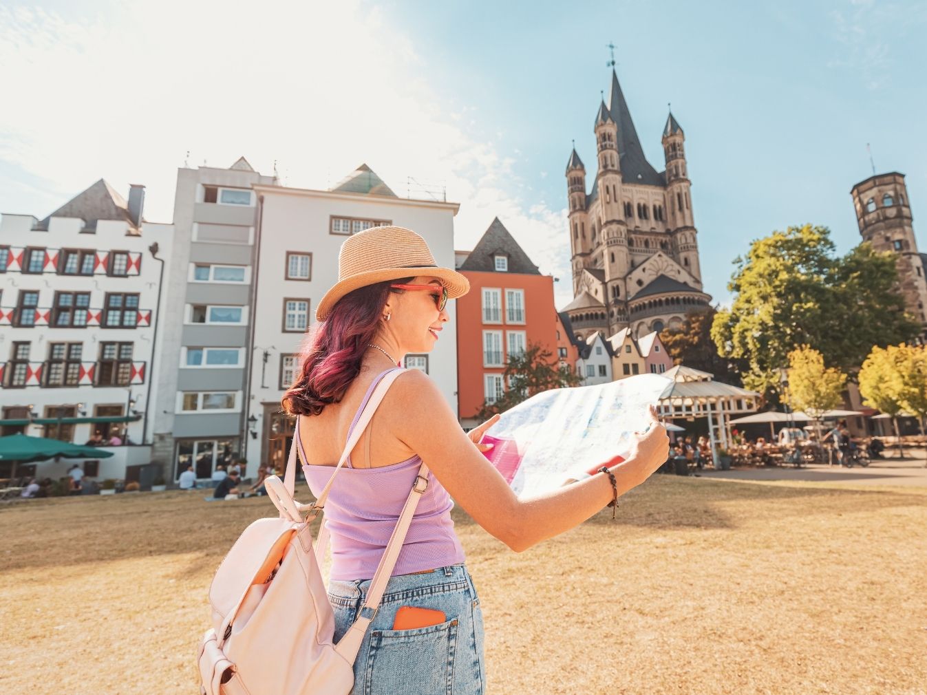  Eine Frau steht mit Stadtplan an der Rheinpromenade in Köln nahe den bunten Häusern 