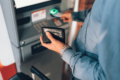 Person steckt Karte in Geldautomaten