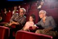 Großeltern sitzen mit ihrer Enkelin im Kino.