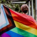 person mit queer pride flagge