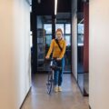 Frau kommt mit Fahrrad ins Büro