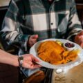 Kellnerin serviert Mann ein Schnitzel mit Beilagen im Restaurant