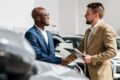 Zwei Männer schütteln Hände im Autohaus