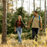 Ein Mann und eine Frau halten sich bei der Hand und gehen im Wald wandern