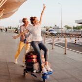 Mann schiebt Frau auf Kofferwagen am Flughafen